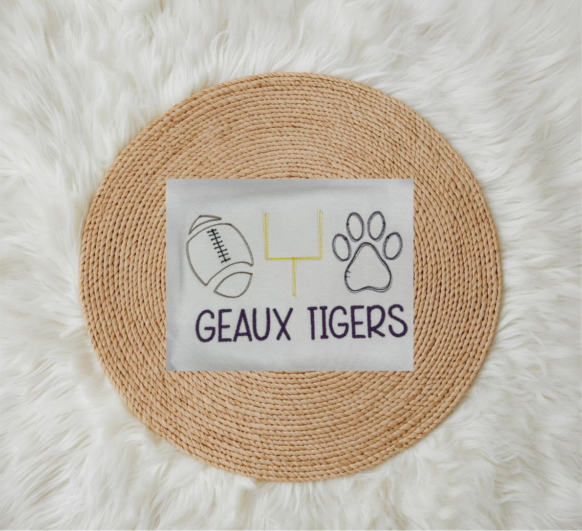 Round woven placemat with a white square featuring sports-themed design and 'GEaux Tigers' text on a fluffy white surface.