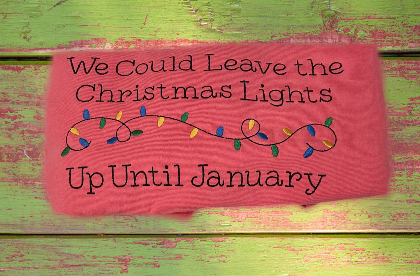 Pink sign with Christmas lights and text on a green wooden background